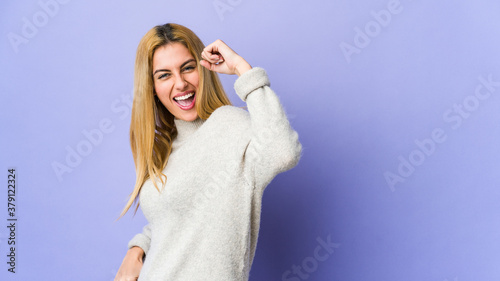Young blonde woman isolated on purple background cheering carefree and excited. Victory concept.