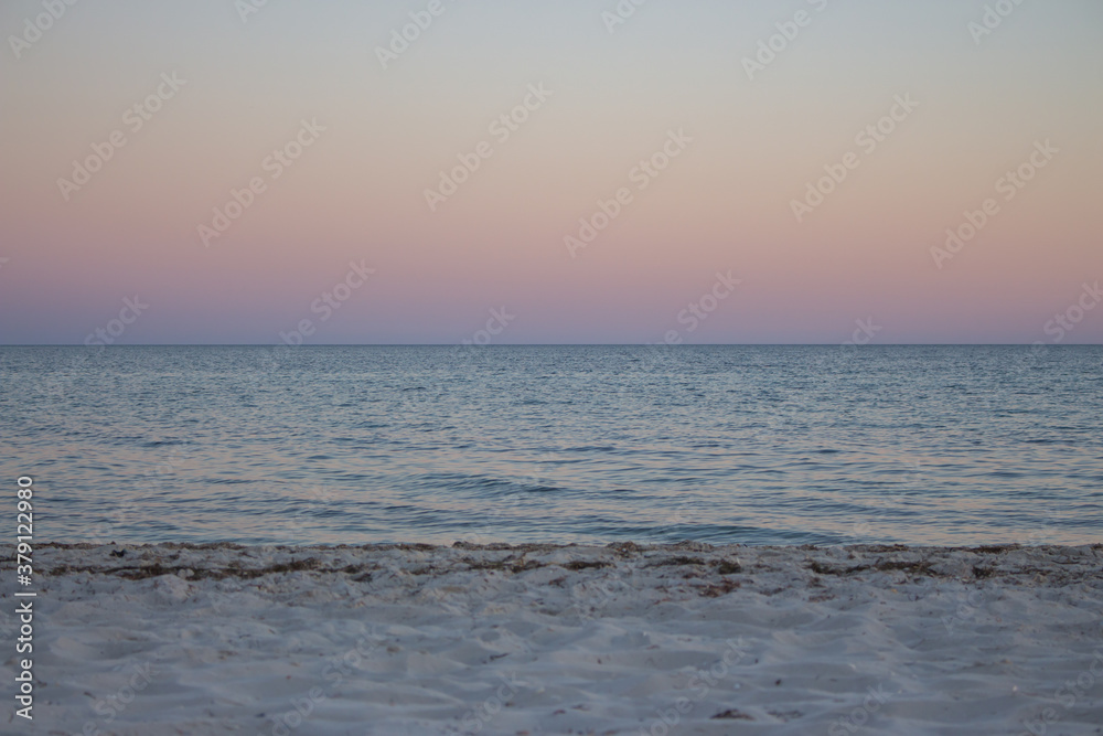 Beautiful sunset on the beach. Calm evening over the sea. Colorful evening sky on island. Seaside landscape. White sand beach and calm sea in evening dusk. Summer vacation. Beautiful sunset on the beach. Calm evening over the sea. Colorful evening sky on island. Seaside landscape. White sand beach and calm sea in evening dusk. Summer vacation.