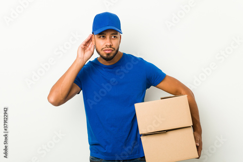 Young south-asian delivery man trying to listening a gossip.