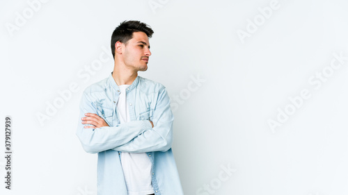 Young caucasian man isolated on white background suspicious, uncertain, examining you. © Asier