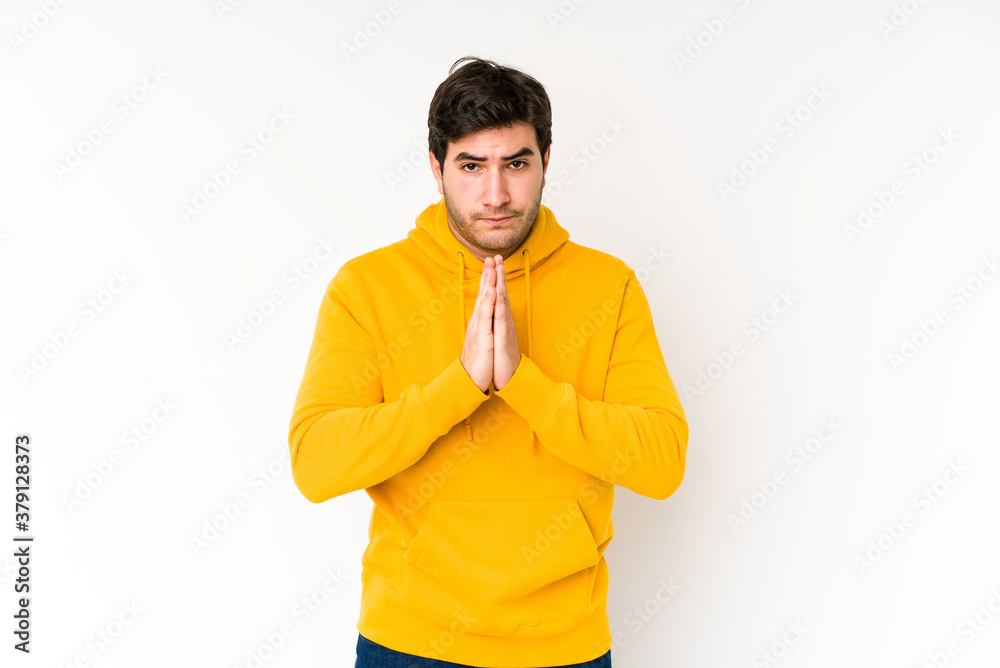 Young man isolated on white background praying, showing devotion, religious person looking for divine inspiration. Young man isolated on white background praying, showing devotion, religious person looking for divine inspiration.