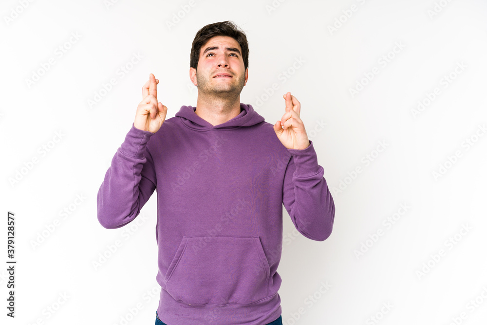 Young man isolated on white background crossing fingers for having luck Young man isolated on white background crossing fingers for having luck