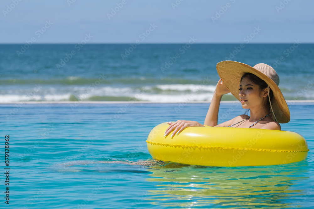 Happy woman asia enjoying beach relaxing joyful in summer by tropical blue water. Beautiful bikini orange tan skin model happy on travel wearing beach sun hat on rayong beach, Rayong, Thailand