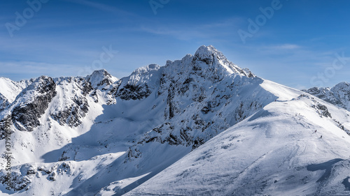 View from Kasprowy Wierch on adventurers climbing on Swinica mountain peak at winter. Tatra Mountains range with snow capped mountain peaks, Poland © Dawid