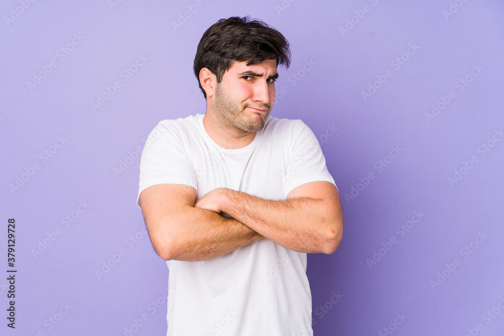 Young man isolated on purple background frowning face in displeasure, keeps arms folded. Young man isolated on purple background frowning face in displeasure, keeps arms folded.