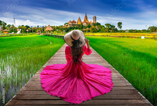 Thai female tourist sits on a wooden bridge looking at Wat Tham Sua in Kanchanaburi, Thailand. photo