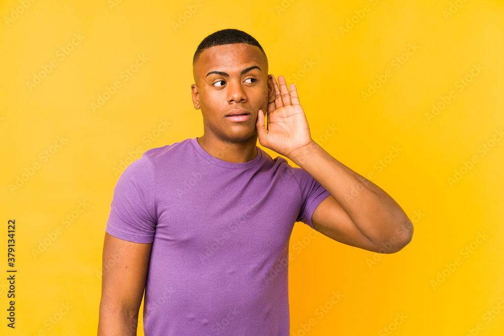 Young latin man isolated on yellow background trying to listening a gossip. Young latin man isolated on yellow background trying to listening a gossip.