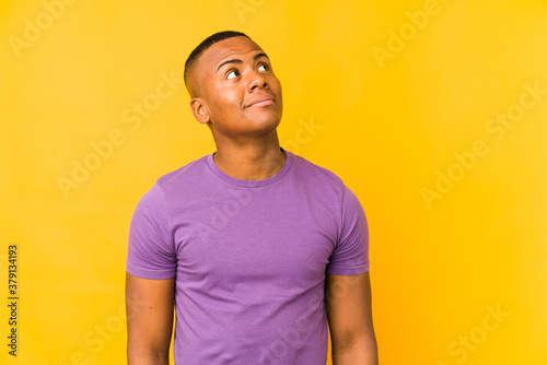 Young latin man isolated on yellow background dreaming of achieving goals and purposes
