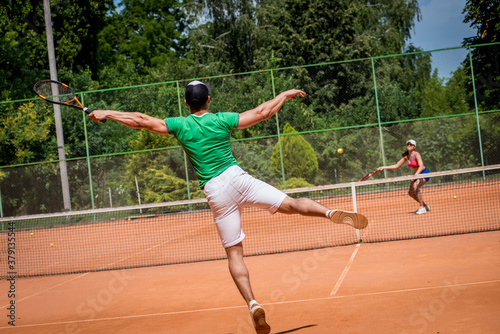 Young athletic couple playing tennis on the court.