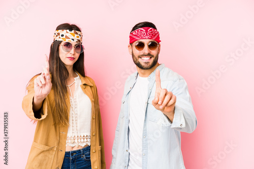 Young caucasian couple wearing a music festival clothes isolated showing number one with finger.