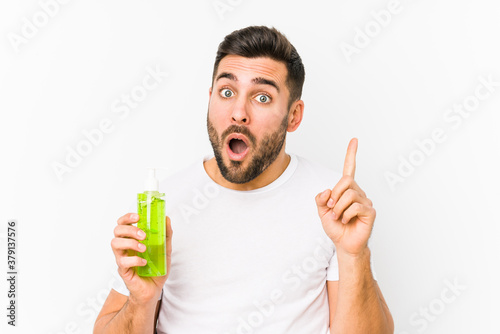 Young caucasian man holding a moisturizer with aloe vera isolated having some great idea, concept of creativity.