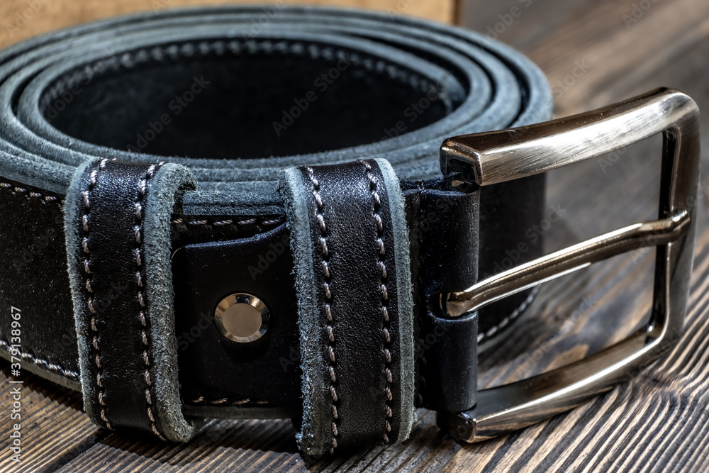 Belt with metal buckle. The belt is rolled up, next to a gift box. Template for the design of leather accessories. Background, shiny metal belt buckle. Abstract background. Texture background.