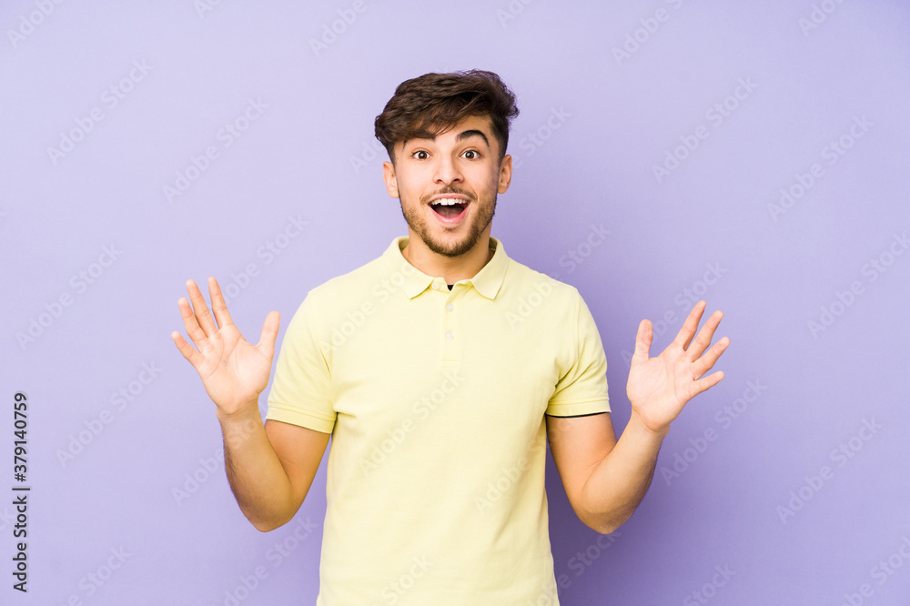 Young arabian man isolated on a purple background receiving a pleasant surprise, excited and raising hands. Young arabian man isolated on a purple background receiving a pleasant surprise, excited and raising hands.