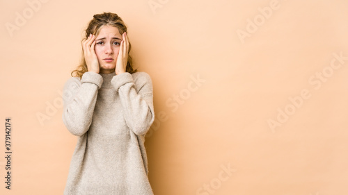 Young caucasian woman isolated on beige background crying, unhappy with something, agony and confusion concept.