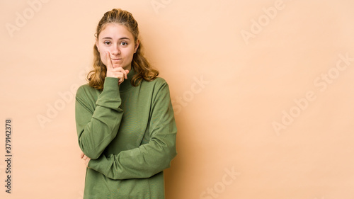 Young caucasian woman isolated on beige background unhappy looking in camera with sarcastic expression. © Asier