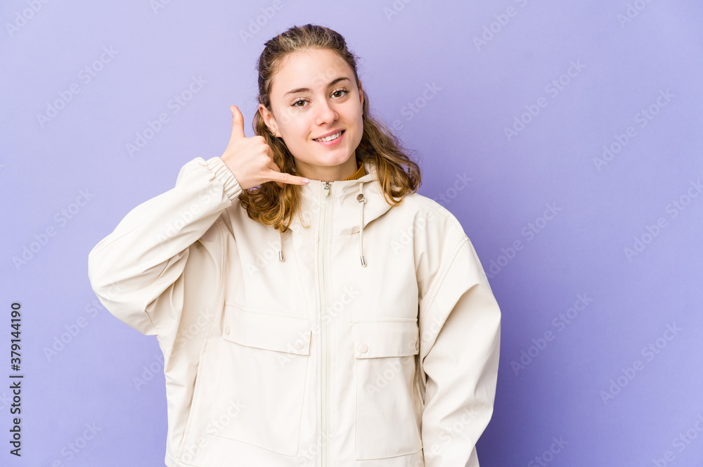 Young caucasian woman on purple background showing a mobile phone call gesture with fingers. Young caucasian woman on purple background showing a mobile phone call gesture with fingers.