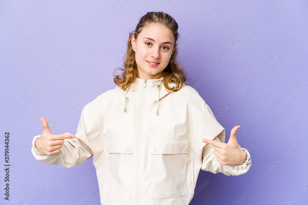 Young caucasian woman on purple background points down with fingers, positive feeling.