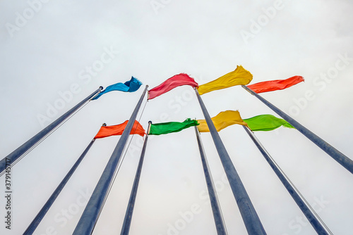 Plain monophonic color disheveled flags on flagpole waving on gray sky background