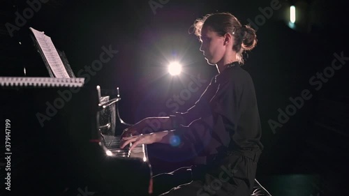 Slow motion of vigorous piano playing. The pianist performs on stage in the spotlight photo