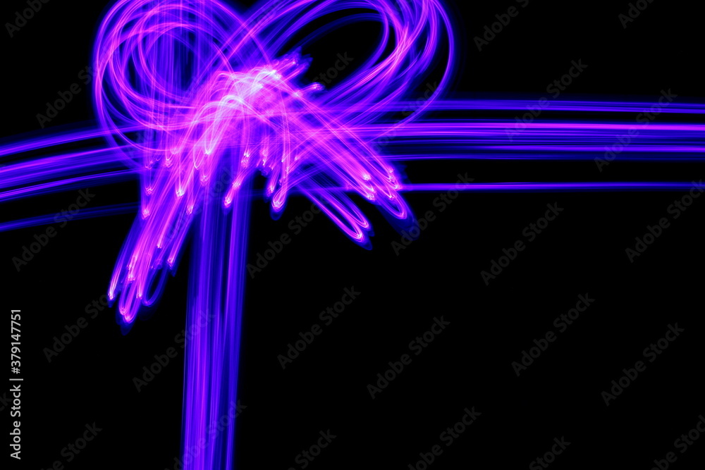 Long exposure photograph of purple neon colour in an abstract gift bow design, parallel lines pattern against a black background. Light painting photography.