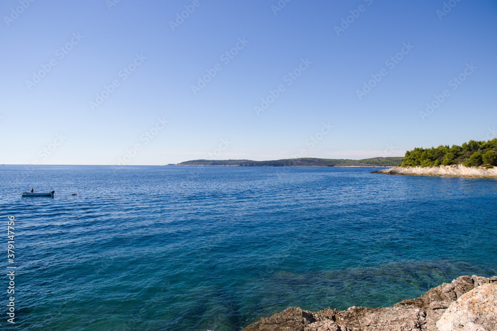 Vue d'une belle mer calme et turquoise, avec ciel dégagé par temps ensoleillé, depuis une plage rocheuse, en Croatie