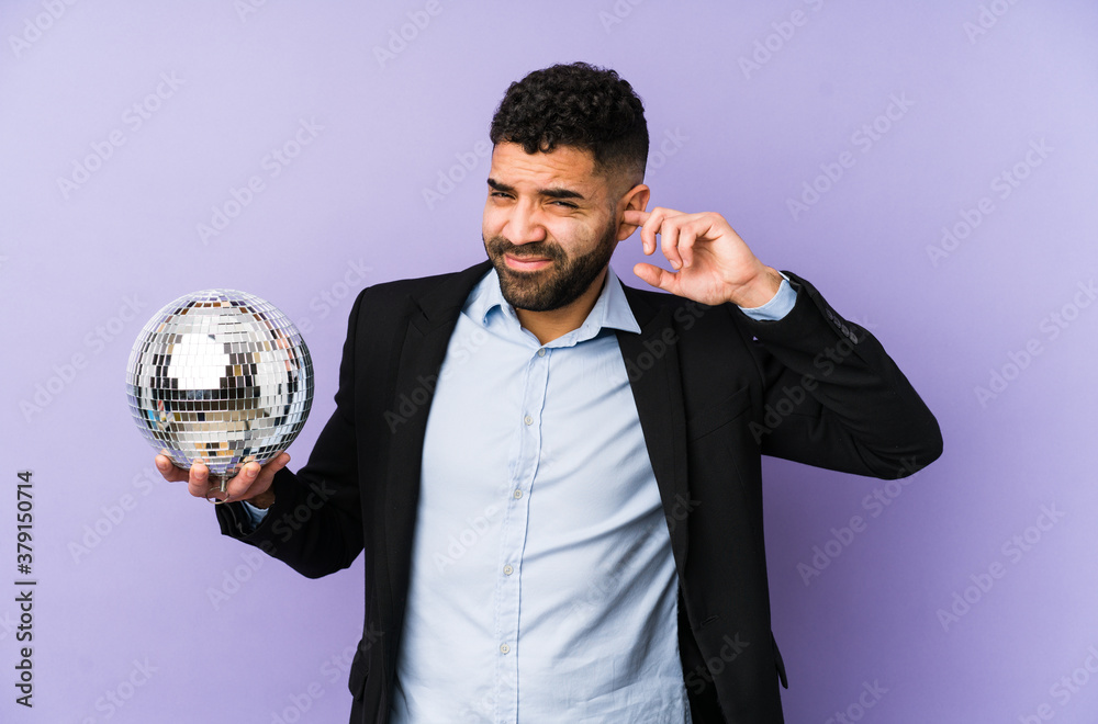 Young latin man holding a party ball isolated Young latin man holding a waffle isolated covering ears with hands.< mixto > Young latin man holding a party ball isolated Young latin man holding a waffle isolated covering ears with hands.< mixto >
