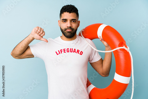 Young latin lifeguard man isolated showing a dislike gesture, thumbs down. Disagreement concept. © Asier
