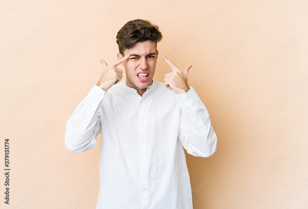 Young caucasian man isolated on beige background showing a disappointment gesture with forefinger.