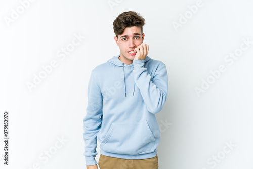 Young caucasian man isolated on white background biting fingernails, nervous and very anxious.