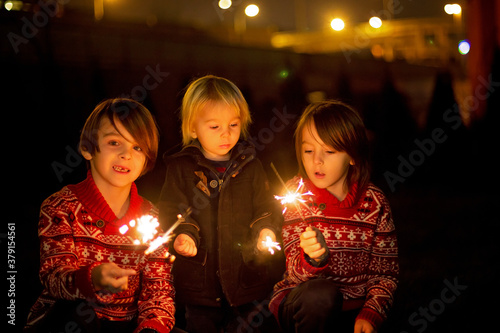 Waist up portrait of happy children celebrating New Year together and lighting sparklers