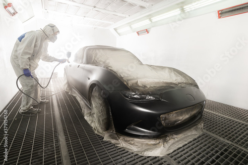 Foto Auto body repair series: Mechanic painting black sports car in paint booth
