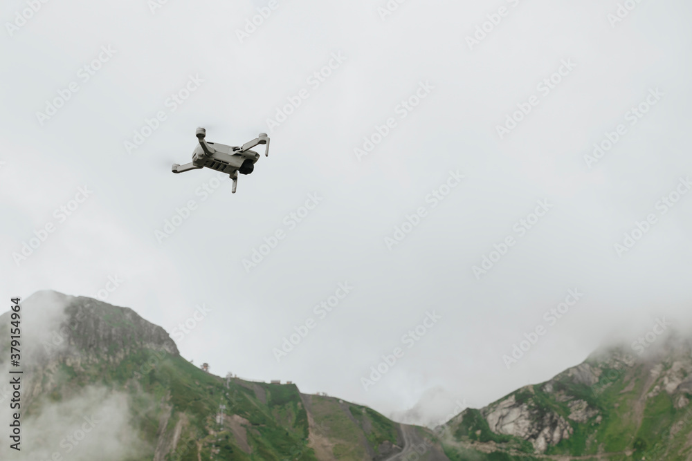 Flying photography drone in the cloudy sky in the mountains, moody weather, natural colors Flying photography drone in the cloudy sky in the mountains, moody weather, natural colors