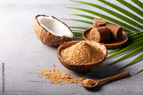 Granular and block shape of organic brown palm sugar on grey concrete background.