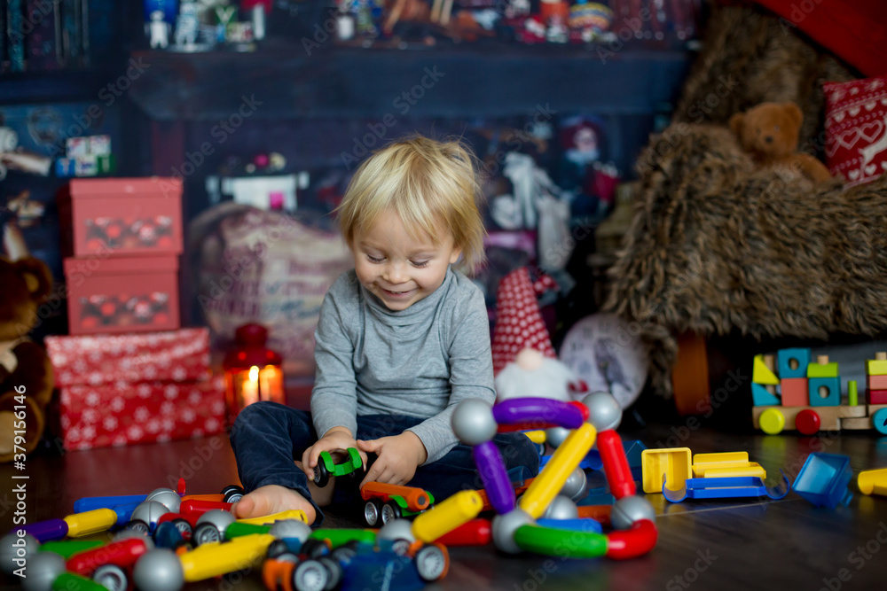 Sweet blonde toddler boy, playing with plastic construction, making different shapes Sweet blonde toddler boy, playing with plastic construction, making different shapes