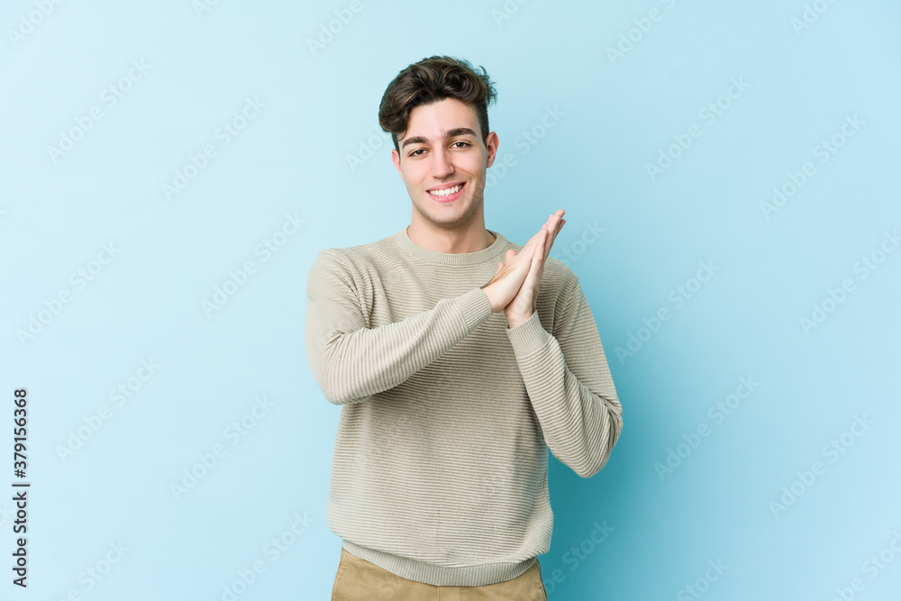 Young caucasian man isolated on blue background feeling energetic and comfortable, rubbing hands confident.