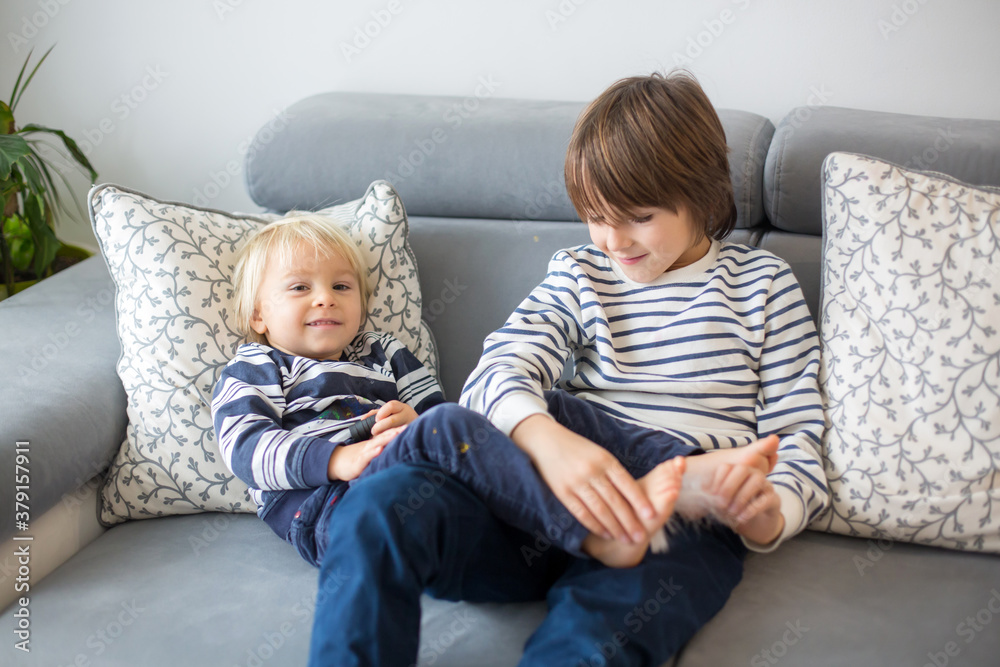 Little toddler and his older brother, having fun at home, tickling and giggle Little toddler and his older brother, having fun at home, tickling and giggle