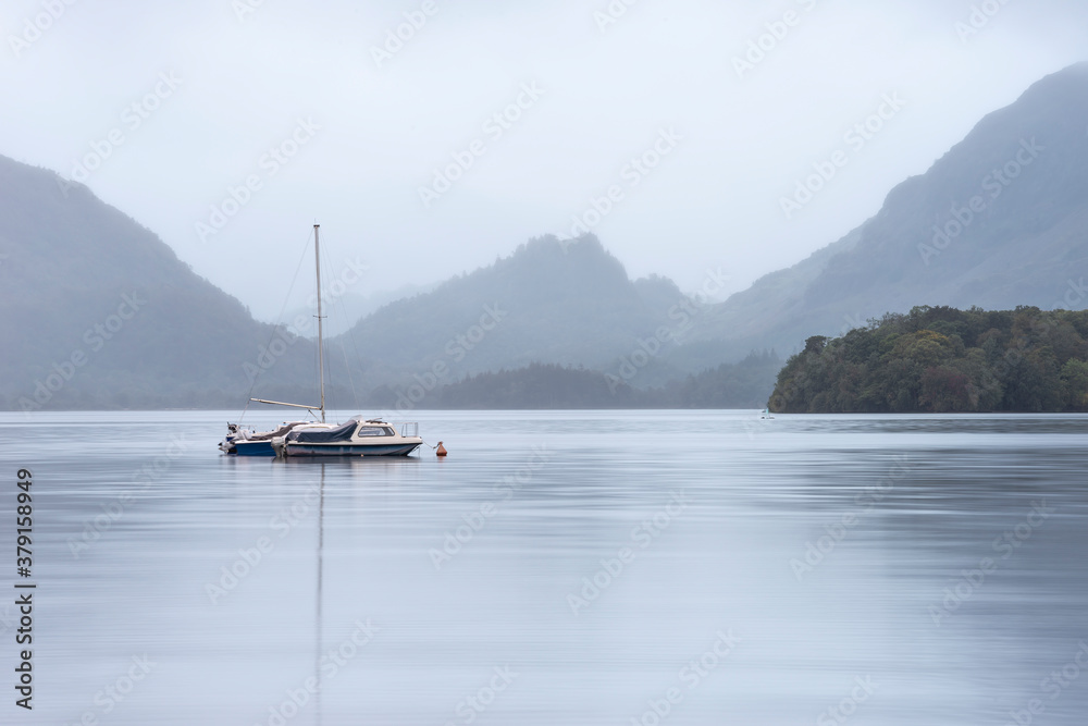 Stunning landscape image of Derwentwater in English Lake District during late Summer with still water and misty mountains in the distance