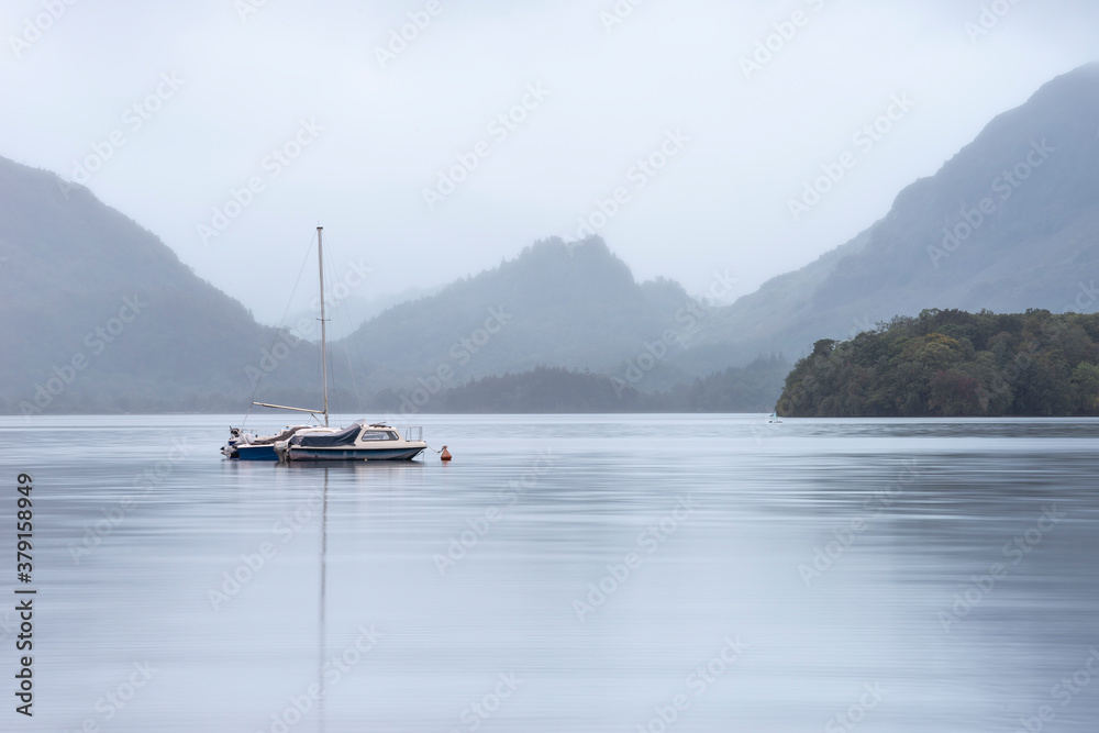 Stunning landscape image of Derwentwater in English Lake District during late Summer with still water and misty mountains in the distance Stunning landscape image of Derwentwater in English Lake District during late Summer with still water and misty mountains in the distance