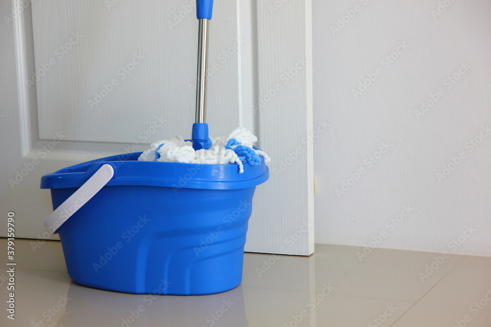 the new mop claning with blue plastic containerin front of white door the new mop claning with blue plastic containerin front of white door