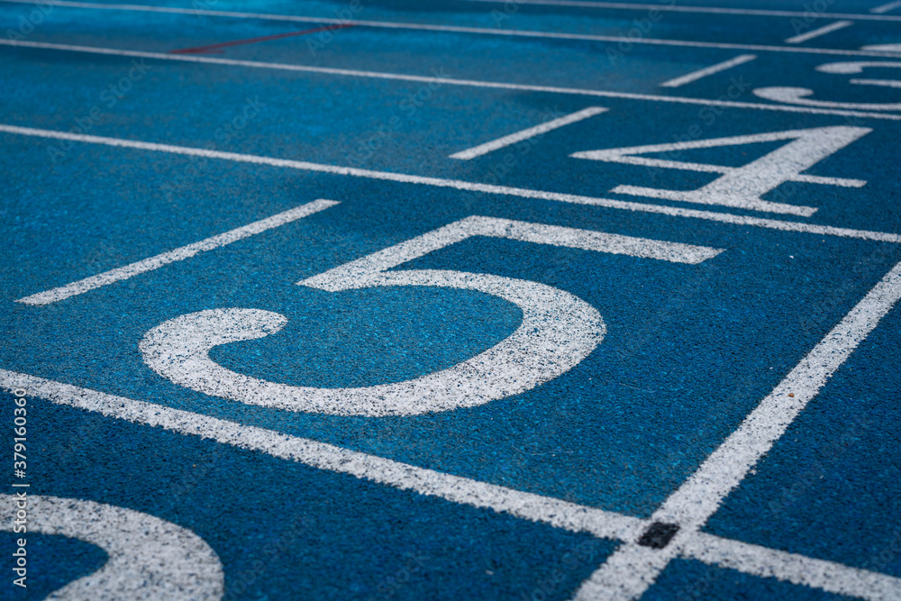 Professional running track of blue rubber surface with standard line, sport background photo. Close-up and selective focus.