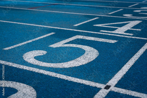Professional running track of blue rubber surface with standard line, sport background photo. Close-up and selective focus. © Nattawit