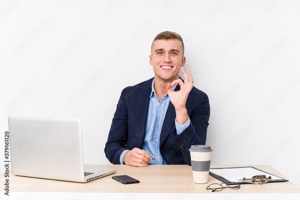 Young business man with a laptop cheerful and confident showing ok gesture. Young business man with a laptop cheerful and confident showing ok gesture.