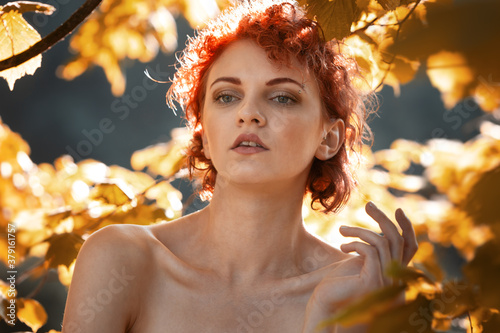Young red-haired woman among the foliage of trees © misu