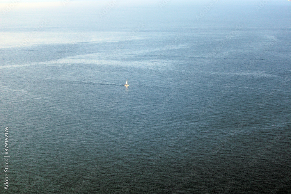 Barca a vela in navigazione solitaria nel mare azzurro