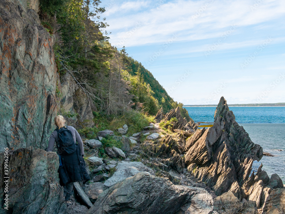 A woman is walking on the shores of Saint Lawrence river, Bic National park, Quebec, Canada