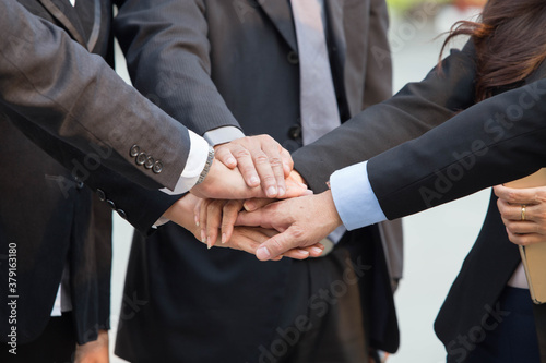 Group of businessmen hold hands together as a team photo