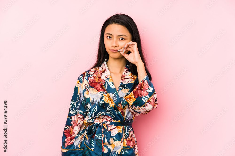 Young chinese woman wearing a asiatic pijama isolated shrugs shoulders and open eyes confused. Young chinese woman wearing a asiatic pijama isolated shrugs shoulders and open eyes confused.