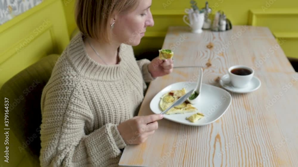 young woman for breakfast eats scrambled eggs. woman eating breakfast in a cafe young woman for breakfast eats scrambled eggs. woman eating breakfast in a cafe