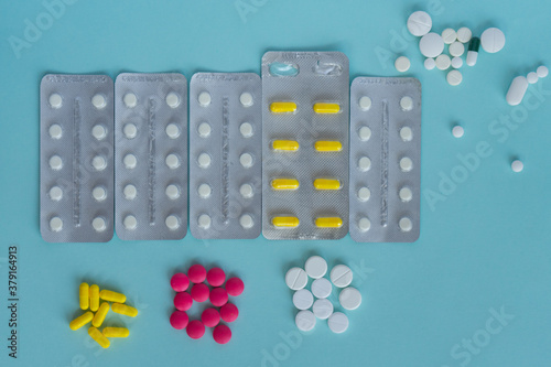 A set of tablets pack and pills in blisters on a blue background. Medical concept. White, yellow, pink tablets of various shapes. Treatment, self-care.