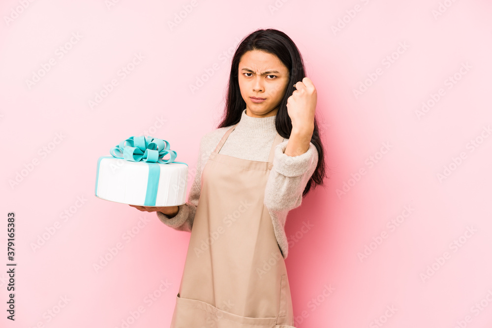 Young chinese woman holding a cake isolated laughing and having fun. Young chinese woman holding a cake isolated laughing and having fun.